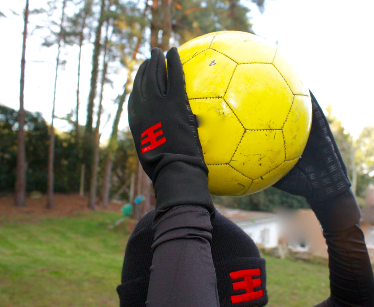 boy wearing defiance gloves holding yellow ball above head 